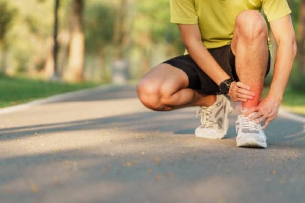 Young adult male with his muscle pain during running. runner man having leg ache due to Ankle Sprains or Achilles Tendonitis. Sports injuries and medical concept