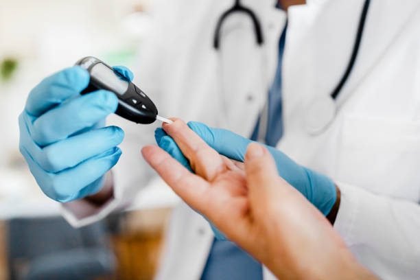 Geriatric male nurse measures the blood sugar level of a patient